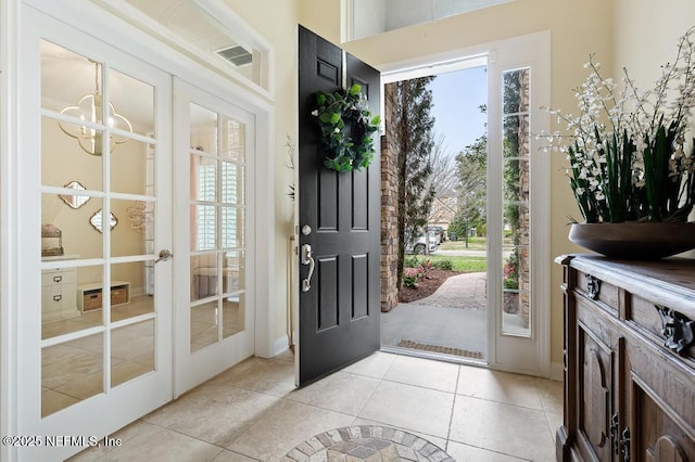 foyer with light tile patterned floors, plenty of natural light, and a chandelier