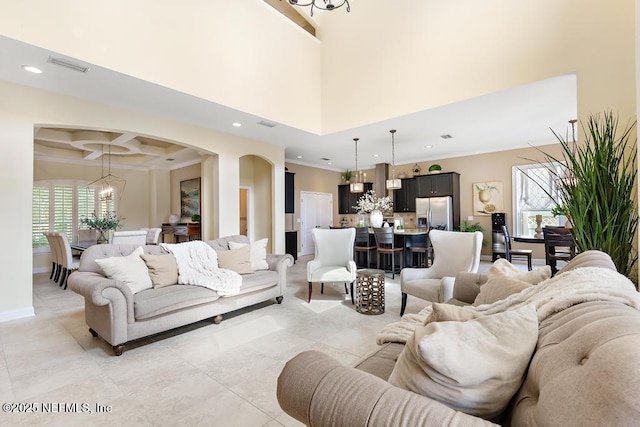 living area with plenty of natural light, arched walkways, coffered ceiling, and crown molding