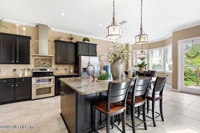 kitchen with a center island with sink, visible vents, decorative backsplash, wall chimney exhaust hood, and stainless steel appliances