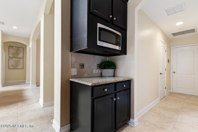 corridor featuring arched walkways, visible vents, and baseboards