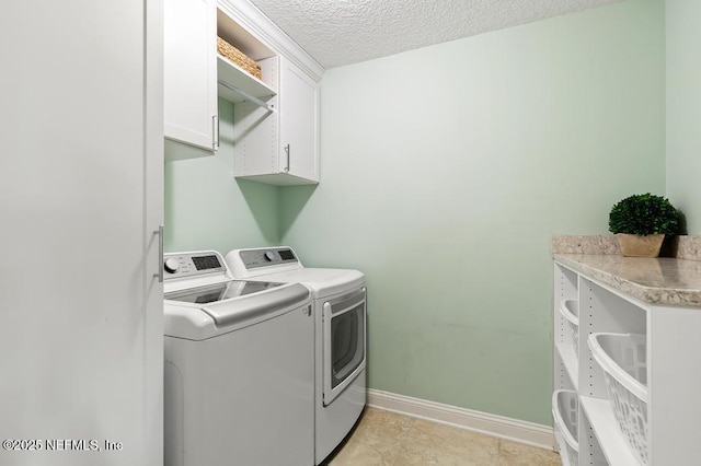 washroom with cabinet space, baseboards, a textured ceiling, and washing machine and clothes dryer