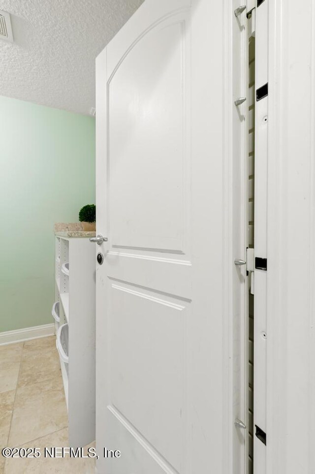 details featuring visible vents, a textured ceiling, and baseboards