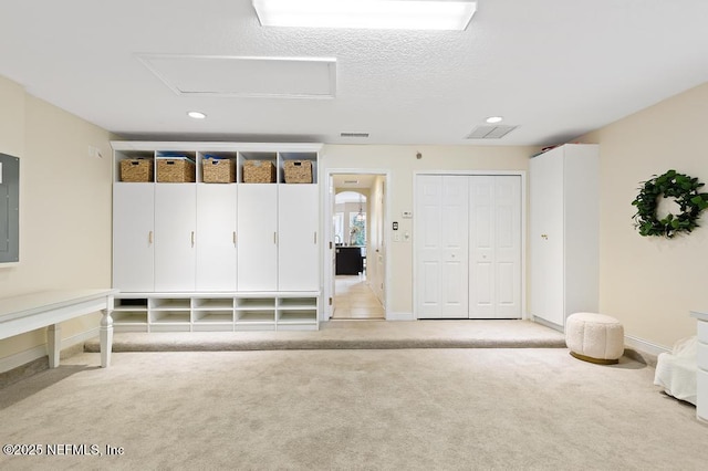 mudroom with attic access, carpet flooring, a textured ceiling, electric panel, and baseboards