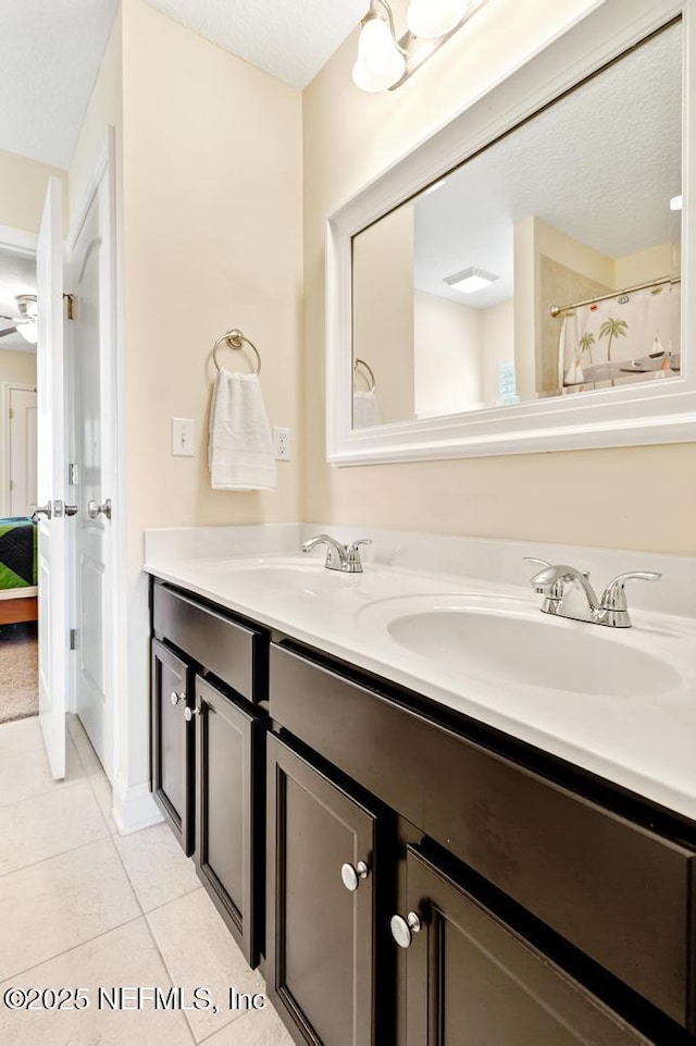 full bath featuring double vanity, tile patterned flooring, a textured ceiling, and a sink