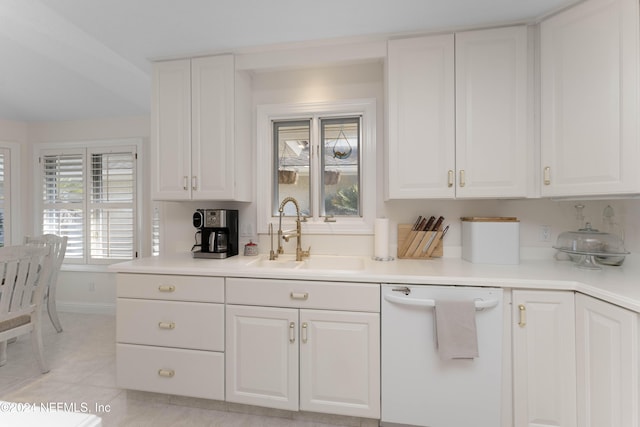 kitchen with light countertops, white dishwasher, a sink, and white cabinetry