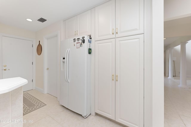 kitchen with visible vents, white refrigerator with ice dispenser, white cabinetry, and ornate columns