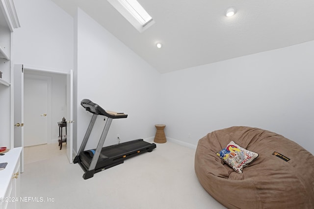 workout room featuring lofted ceiling with skylight, carpet flooring, and baseboards