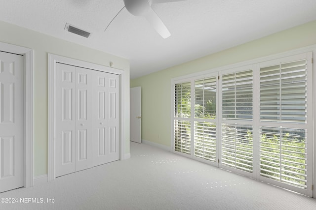 unfurnished bedroom featuring a textured ceiling, carpet flooring, visible vents, and baseboards