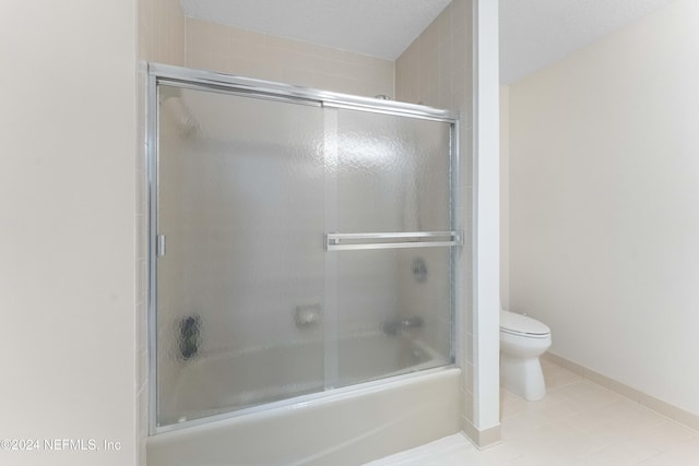 full bath featuring toilet, bath / shower combo with glass door, and tile patterned floors