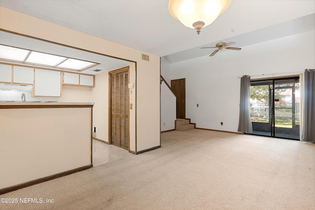 unfurnished living room featuring lofted ceiling, light colored carpet, a ceiling fan, baseboards, and visible vents