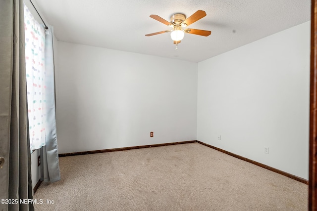 carpeted spare room with a textured ceiling, a ceiling fan, and baseboards