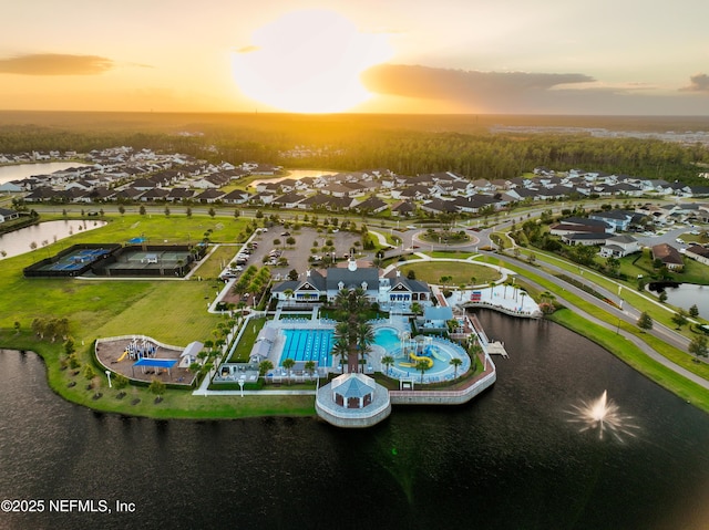 aerial view at dusk with a residential view and a water view