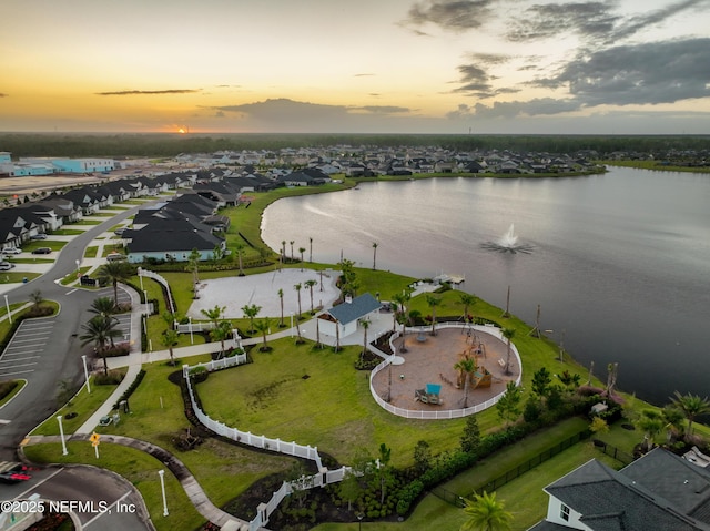 aerial view at dusk with a residential view and a water view