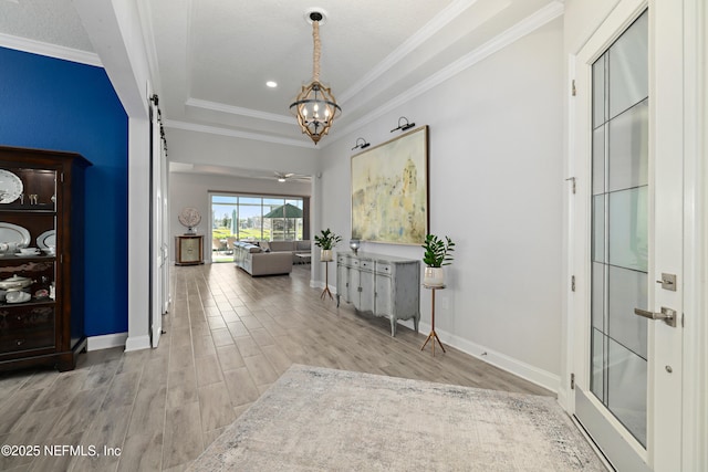 entrance foyer featuring crown molding, baseboards, a barn door, wood finished floors, and a notable chandelier