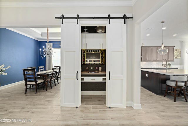 interior space with a sink, a barn door, tasteful backsplash, and crown molding