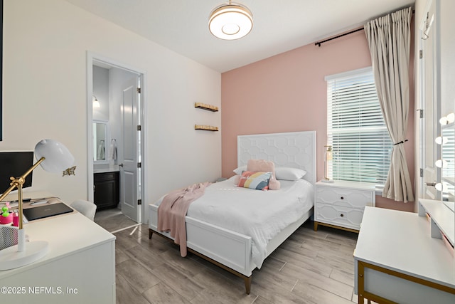 bedroom with wood finish floors and connected bathroom