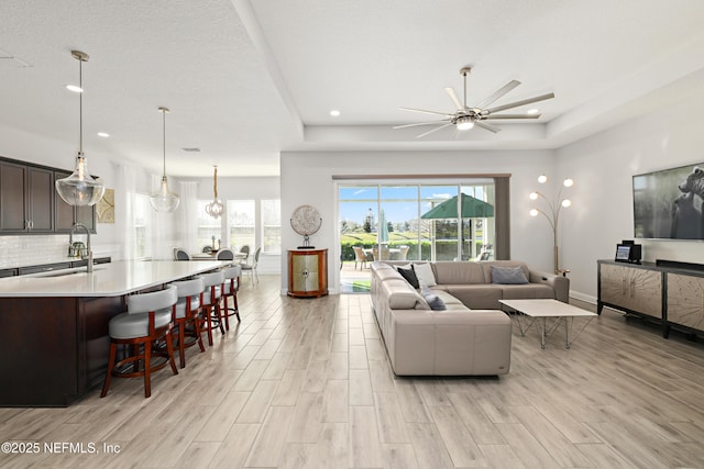 living room featuring light wood finished floors, recessed lighting, a ceiling fan, and baseboards