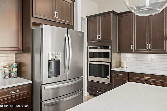 kitchen featuring stainless steel appliances, dark brown cabinetry, and decorative backsplash