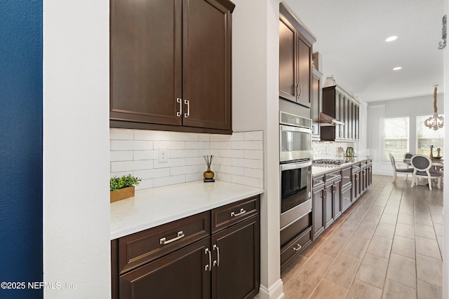 kitchen featuring recessed lighting, dark brown cabinetry, appliances with stainless steel finishes, light countertops, and decorative backsplash