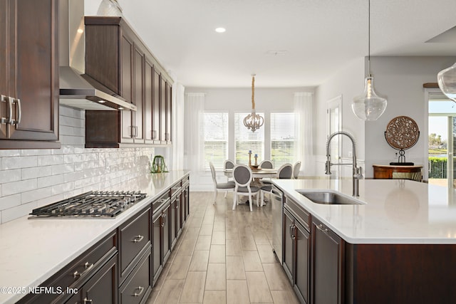 kitchen with a wealth of natural light, appliances with stainless steel finishes, wall chimney exhaust hood, and a sink