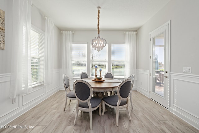 dining space featuring a decorative wall, an inviting chandelier, and wood tiled floor