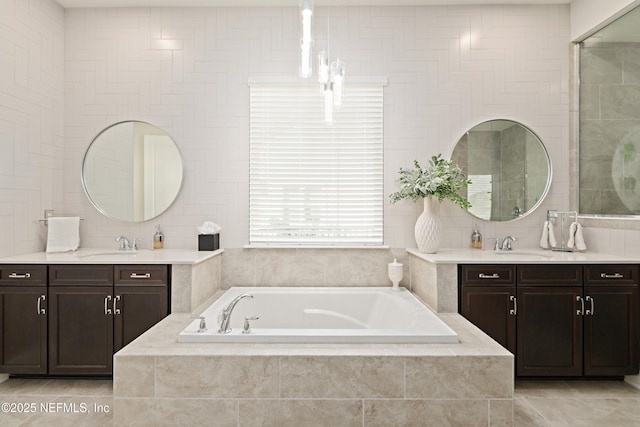 full bathroom with a sink, tile walls, two vanities, and a bath