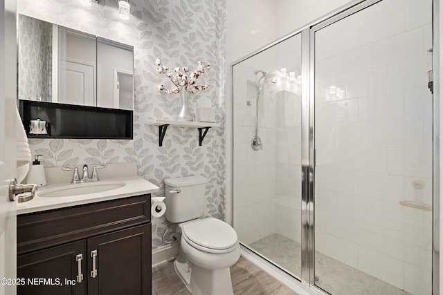 bathroom featuring toilet, a stall shower, vanity, and wallpapered walls