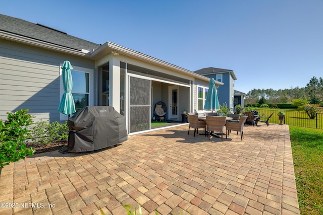 view of patio with outdoor dining space, fence, and a grill