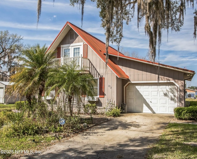 view of front of home with concrete driveway, metal roof, a balcony, and an attached garage