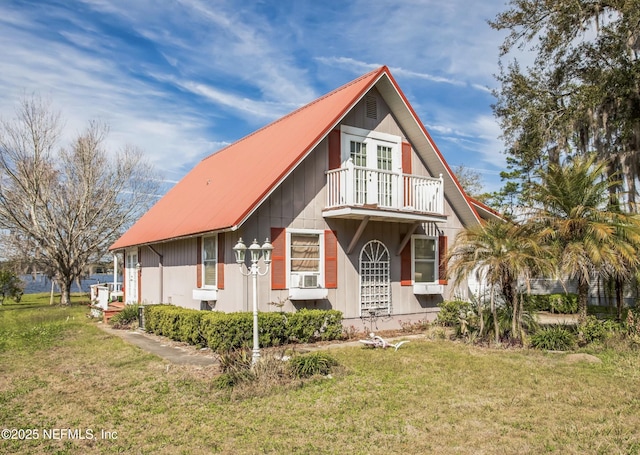 view of front of house with cooling unit, metal roof, a balcony, and a front lawn