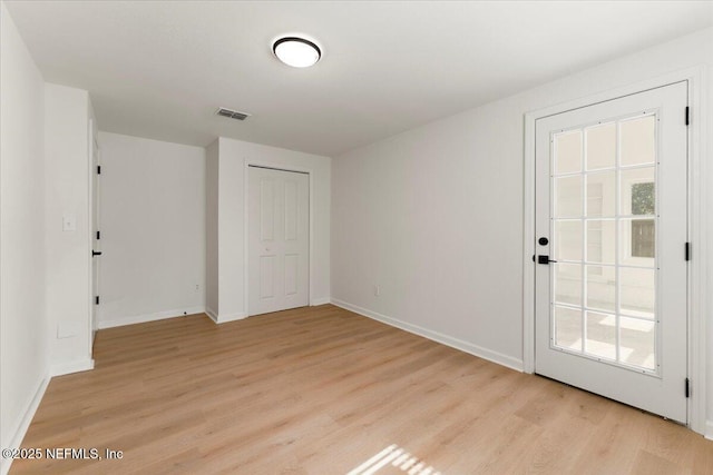 interior space with baseboards, visible vents, and light wood finished floors