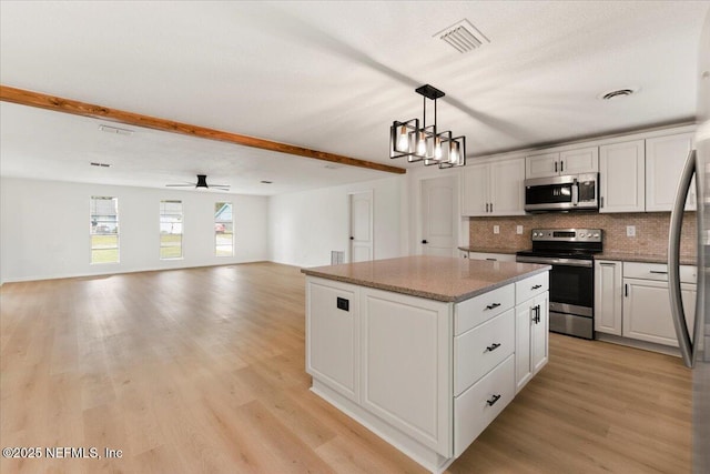 kitchen with light wood finished floors, visible vents, a center island, stainless steel appliances, and backsplash