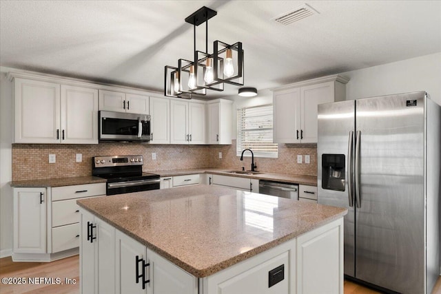 kitchen featuring visible vents, white cabinets, stainless steel appliances, light wood-style floors, and a sink