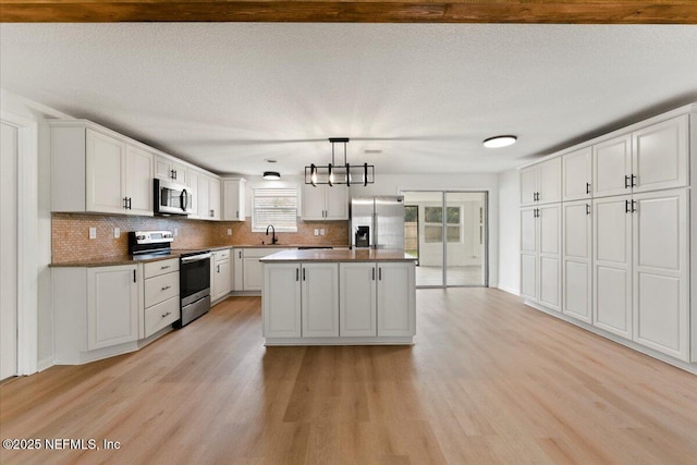 kitchen with stainless steel appliances, light wood-style floors, a sink, and tasteful backsplash