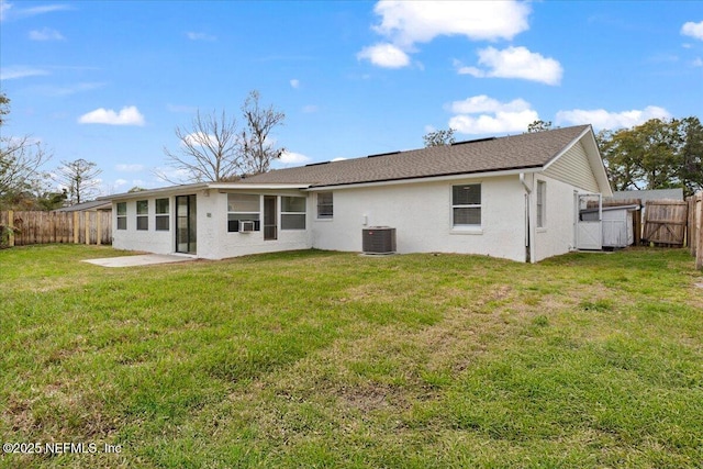 rear view of house with a fenced backyard, a yard, a patio, and central air condition unit