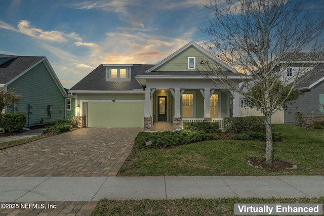 view of front of house featuring an attached garage, decorative driveway, a front lawn, a porch, and brick siding