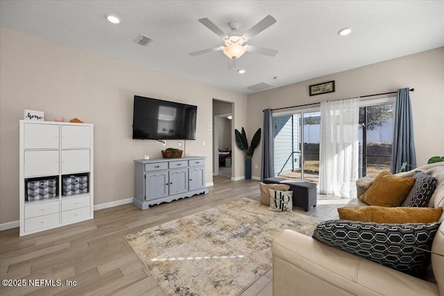 living room with visible vents, baseboards, light wood-style floors, and a ceiling fan