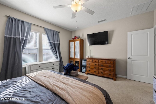 carpeted bedroom with ceiling fan, baseboards, visible vents, and a textured ceiling