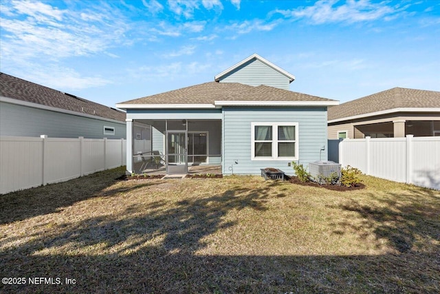 back of property featuring a yard, roof with shingles, a fenced backyard, and a sunroom