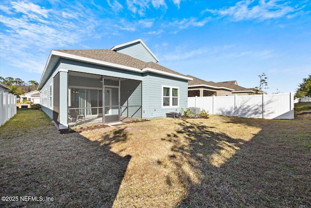 back of property featuring fence, a lawn, a sunroom, and roof with shingles