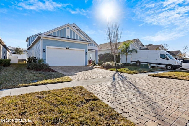 view of front of home with an attached garage, a front lawn, decorative driveway, and board and batten siding