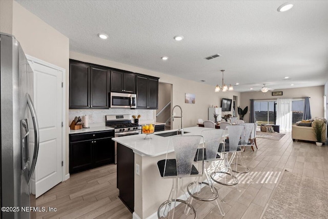 kitchen featuring visible vents, backsplash, appliances with stainless steel finishes, a kitchen breakfast bar, and a sink