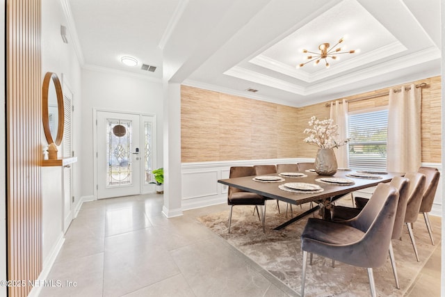 dining room with visible vents, a wainscoted wall, a notable chandelier, ornamental molding, and a decorative wall