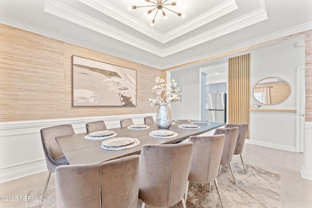 dining area featuring a raised ceiling, an inviting chandelier, wainscoting, and crown molding