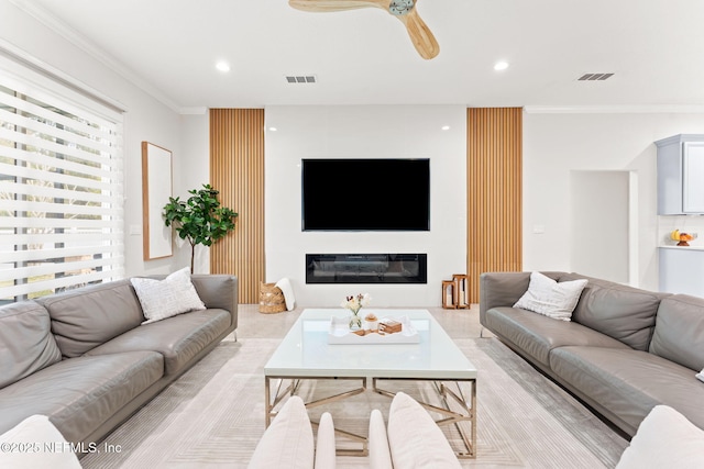 living area with visible vents, recessed lighting, crown molding, and a glass covered fireplace