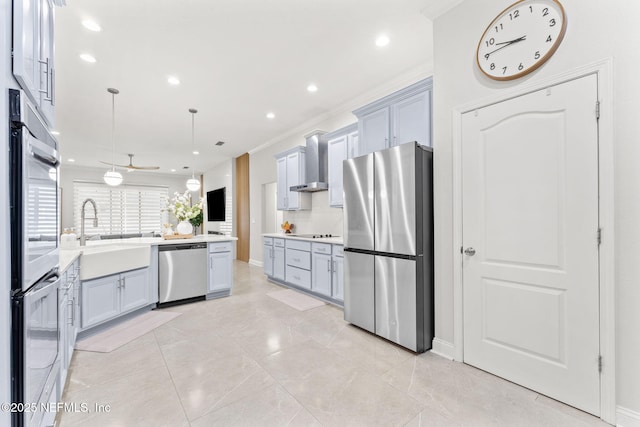 kitchen featuring a sink, gray cabinetry, light countertops, appliances with stainless steel finishes, and wall chimney exhaust hood