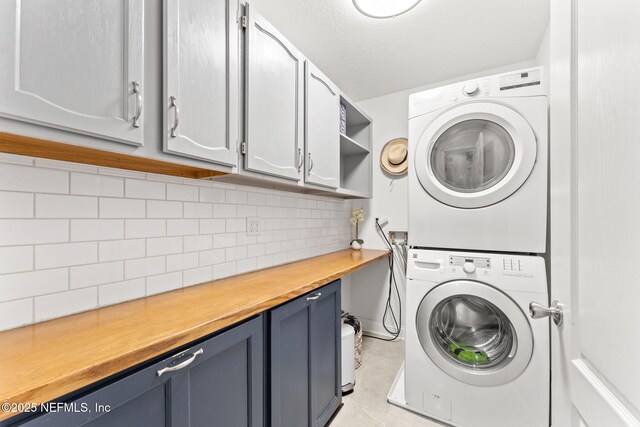 washroom with stacked washer / dryer and cabinet space