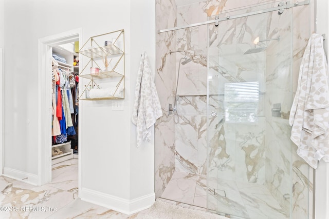 bathroom featuring a spacious closet, baseboards, marble finish floor, and a marble finish shower