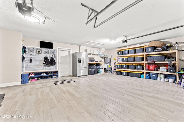 garage with stainless steel fridge and a garage door opener