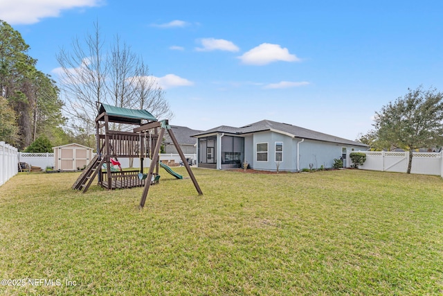 exterior space featuring a fenced backyard, a shed, a playground, an outdoor structure, and a sunroom